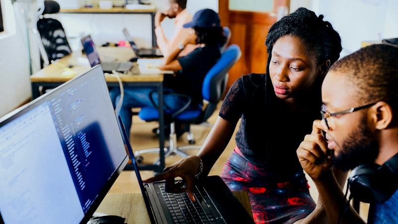 Deux personnes travaillant ensemble devant un écran de code